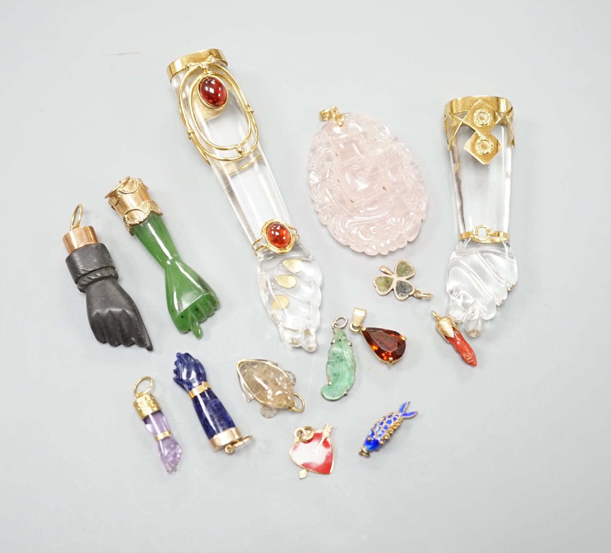 Seven assorted yellow metal or gilt metal mounted clasped hand charm or pendants, largest, 94mm, and seven other smaller charms/pendants including 14k and red enamel heart and an enamelled articulated fish.